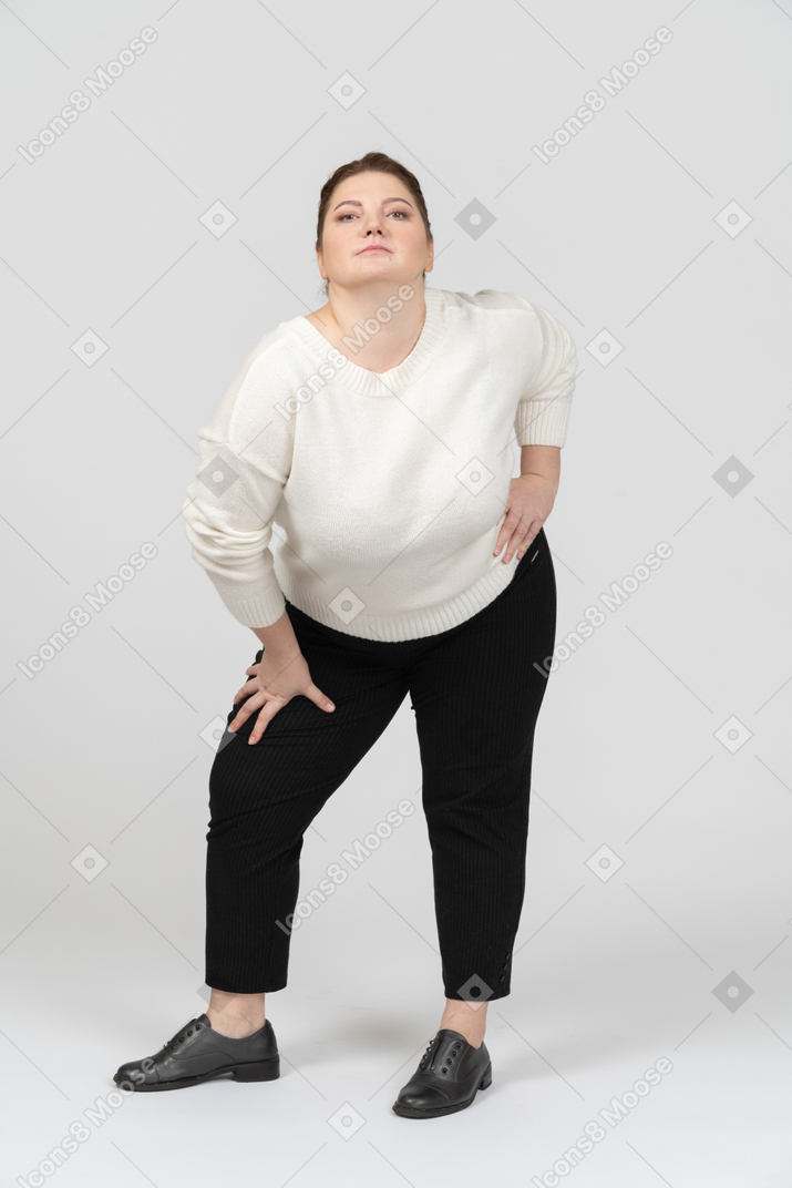 腰に手を当てて立っている白いセーターのふっくらした女性
