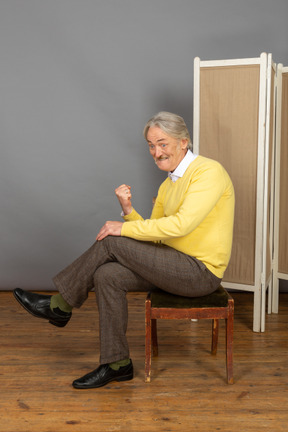 Hombre sentado en una silla y agitando el puño