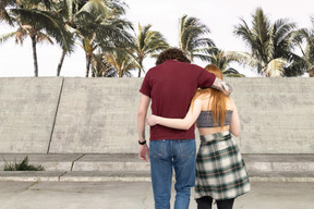 Back view of a young couple hugging and walking