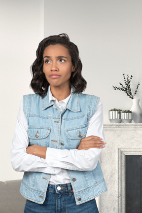 A woman standing in front of a fireplace with her arms crossed