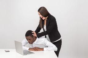 그녀의 직원의 머리를 노트북으로 당기는 공격적인 여성 보스