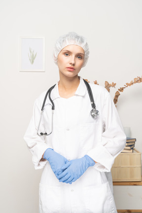 Vista frontal de una doctora joven cansada con estetoscopio mirando a la cámara