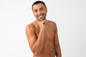 Jovem barechested com um belo sorriso tocando seu queixo