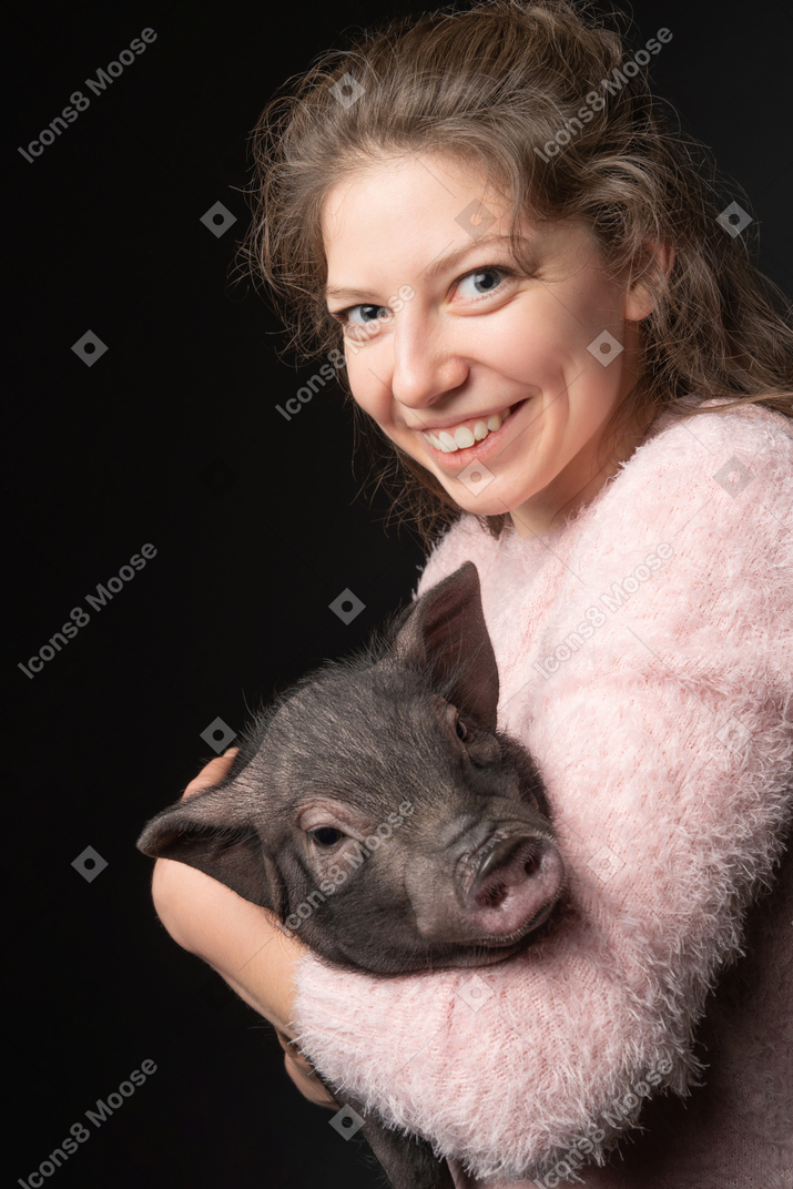 Heureuse jeune femme tenant un cochon miniature