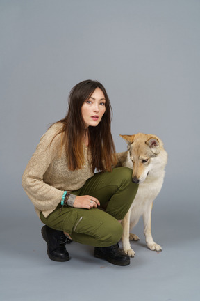 Pleine longueur d'un maître féminin assis près de son chien et regardant la caméra