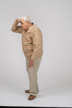 Vista lateral de un anciano con ropa informal buscando a alguien