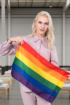 A woman holding a rainbow flag in a room