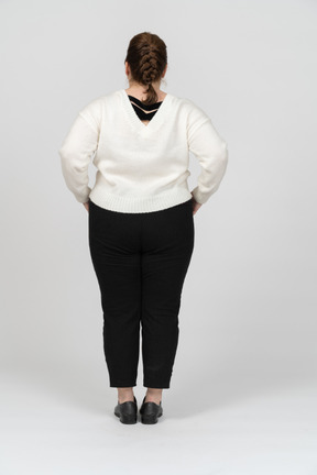 Rear view of a plump woman in white sweater posing