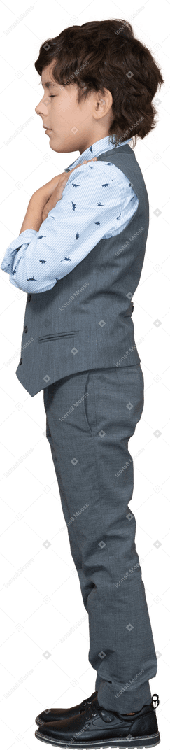Vue latérale d'un garçon en costume gris debout avec les mains sur les épaules