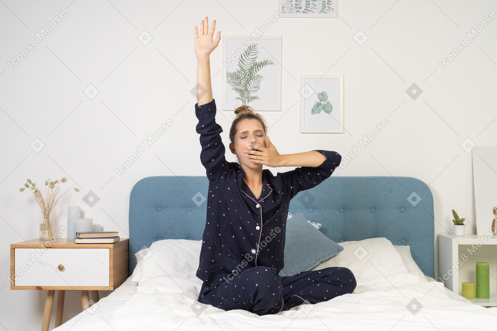 Front view of a young lady in pajamas yawning & staying in bed