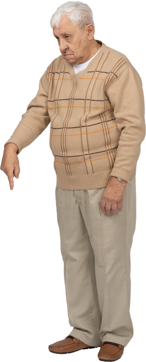 Vista frontal de um velho em roupas casuais, apontando para baixo com o dedo