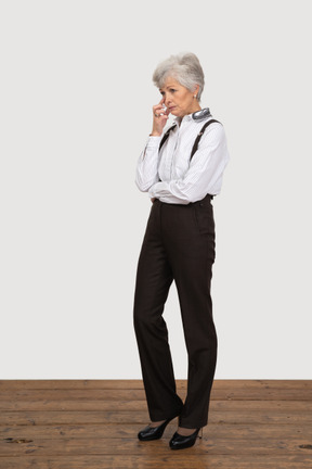Three-quarter view of a thoughtful old lady in office clothing touching face