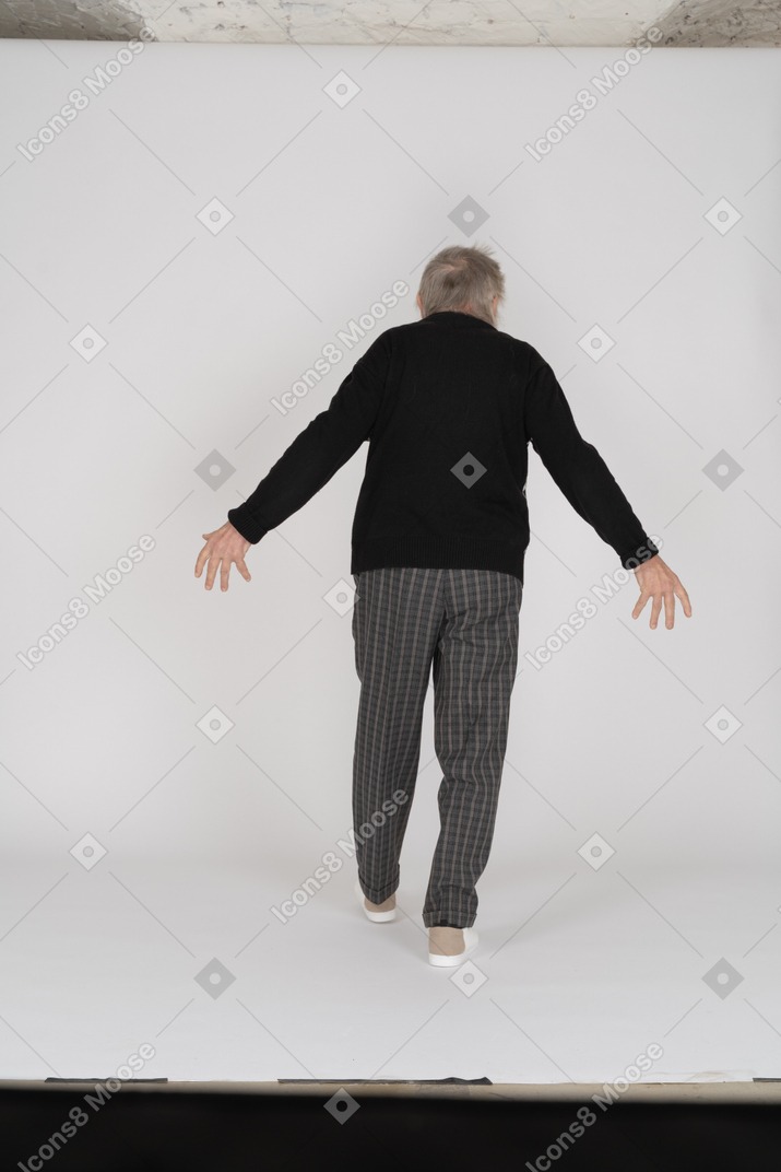 Old man spreading his arms and walking away from camera