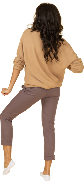 踊る浅黒い肌の若い女性の曲がった膝の背面図