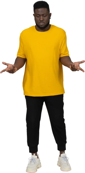 Front view of a thoughtful gesticulating young dark-skinned man in yellow t-shirt