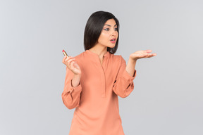 Indian woman in orange top holding lip balm and sending air kiss