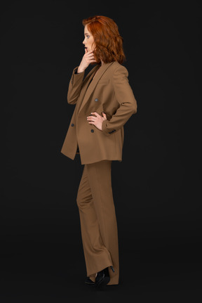 Woman in brown suit thinking and stroking her chin