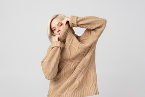 Young woman putting on beige sweater