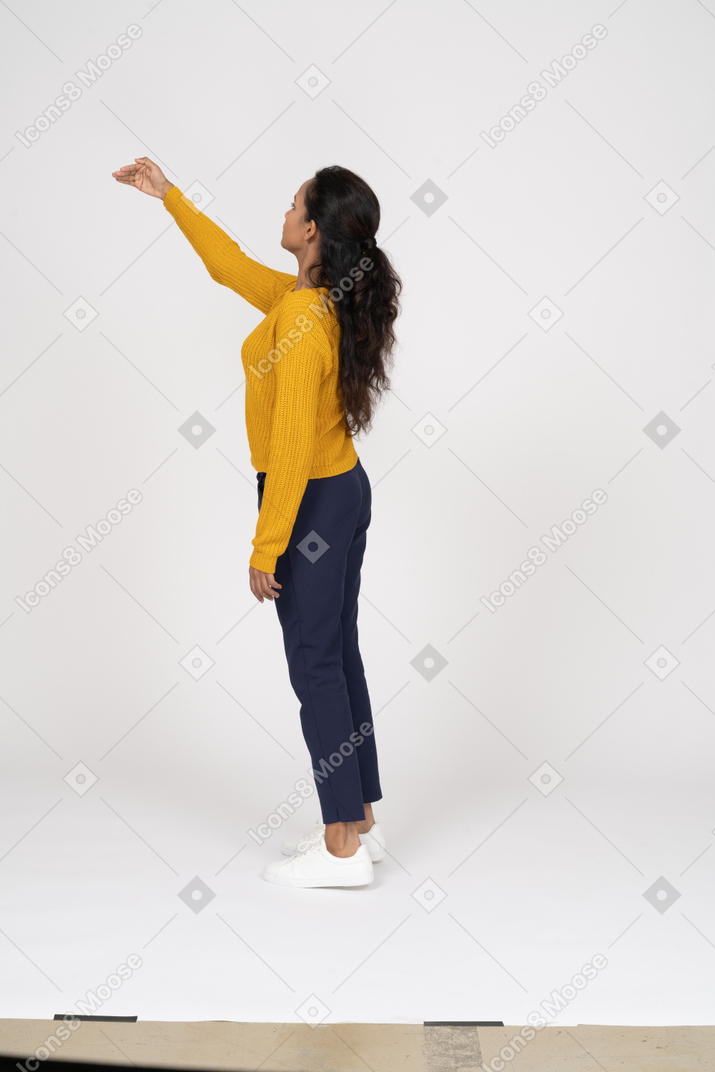 Side view of a girl in casual clothes standing with raised arm