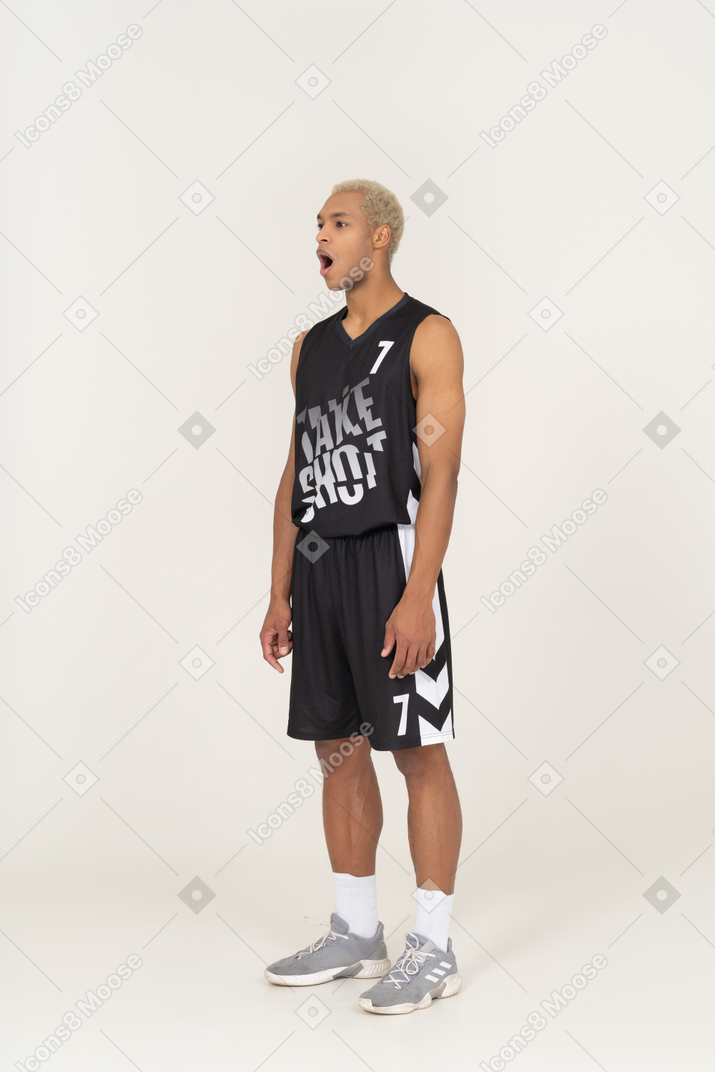 一位震惊的年轻男篮球运动员站着不动的四分之三视图