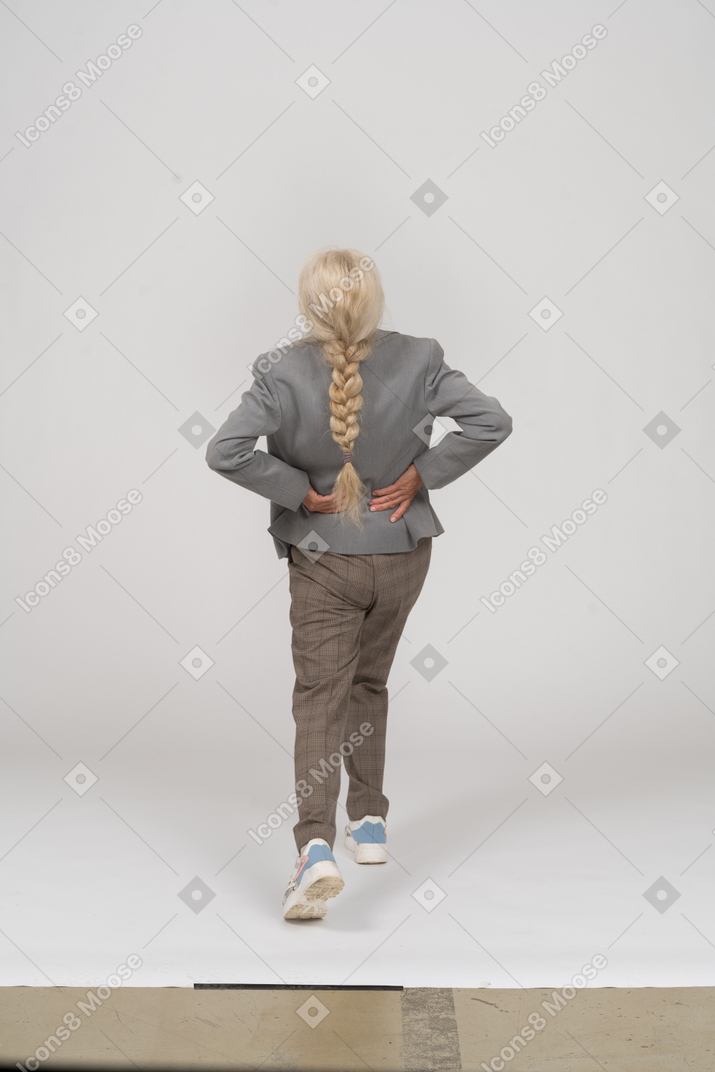 Vista traseira de uma senhora idosa de terno fazendo ioga