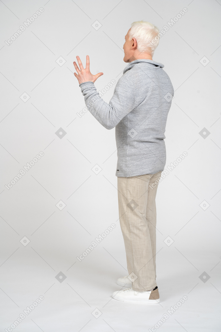 Vista traseira de um homem de pé e levantando a mão esquerda com os dedos abertos