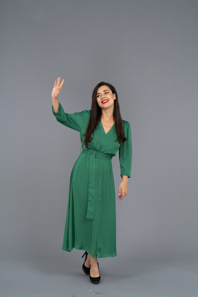 Vista frontale di una giovane donna di saluto in abito verde