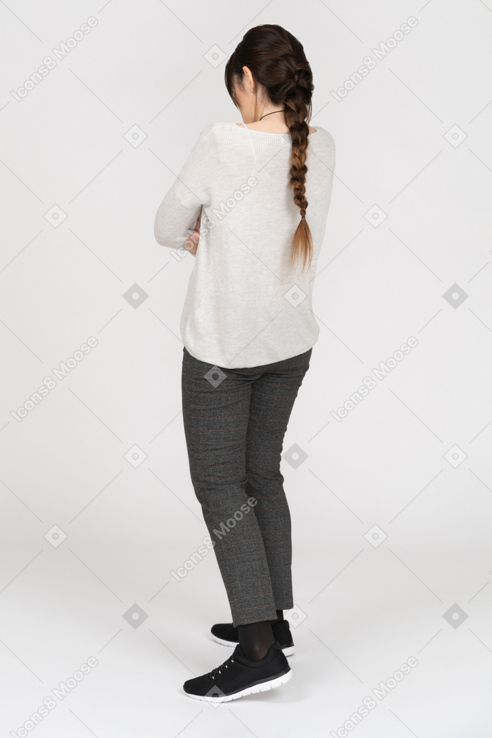 Unrecognizable brunette female standing with folded hands back to camera