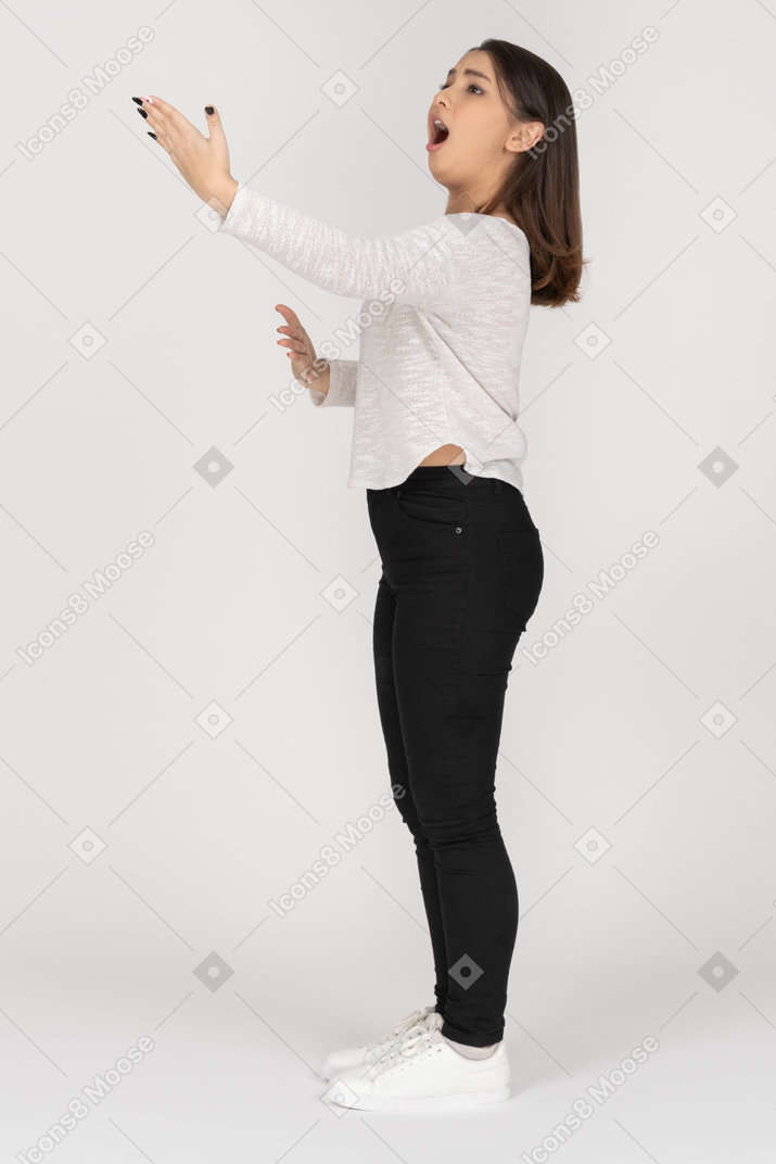 Vista lateral de una joven mujer india cantando en ropa casual extendiendo su brazo