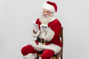 Санта класт держит смартфон и смотрит на него