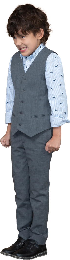 Вид спереди разгневанного мальчика в сером костюме, стоящего со сжатыми кулаками