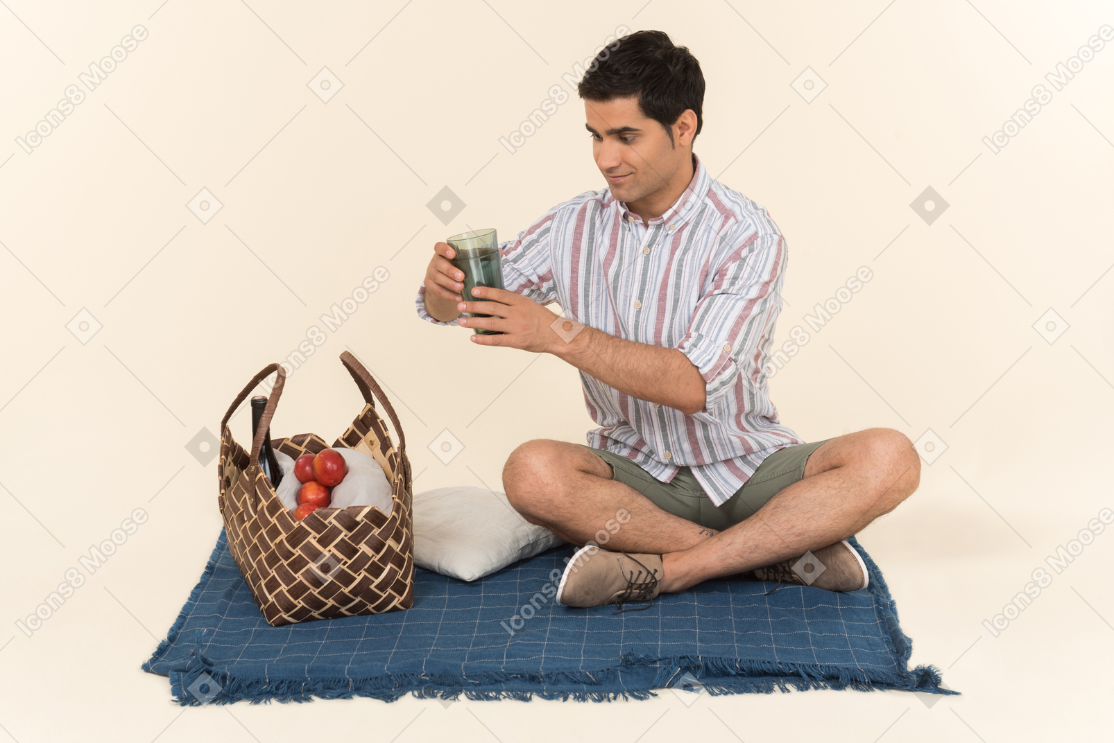 Chico caucásico joven sentado en una manta y sosteniendo copas