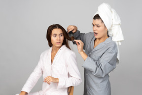 Girl hairstyling her friend's hair  with iron and looks like something went wrong