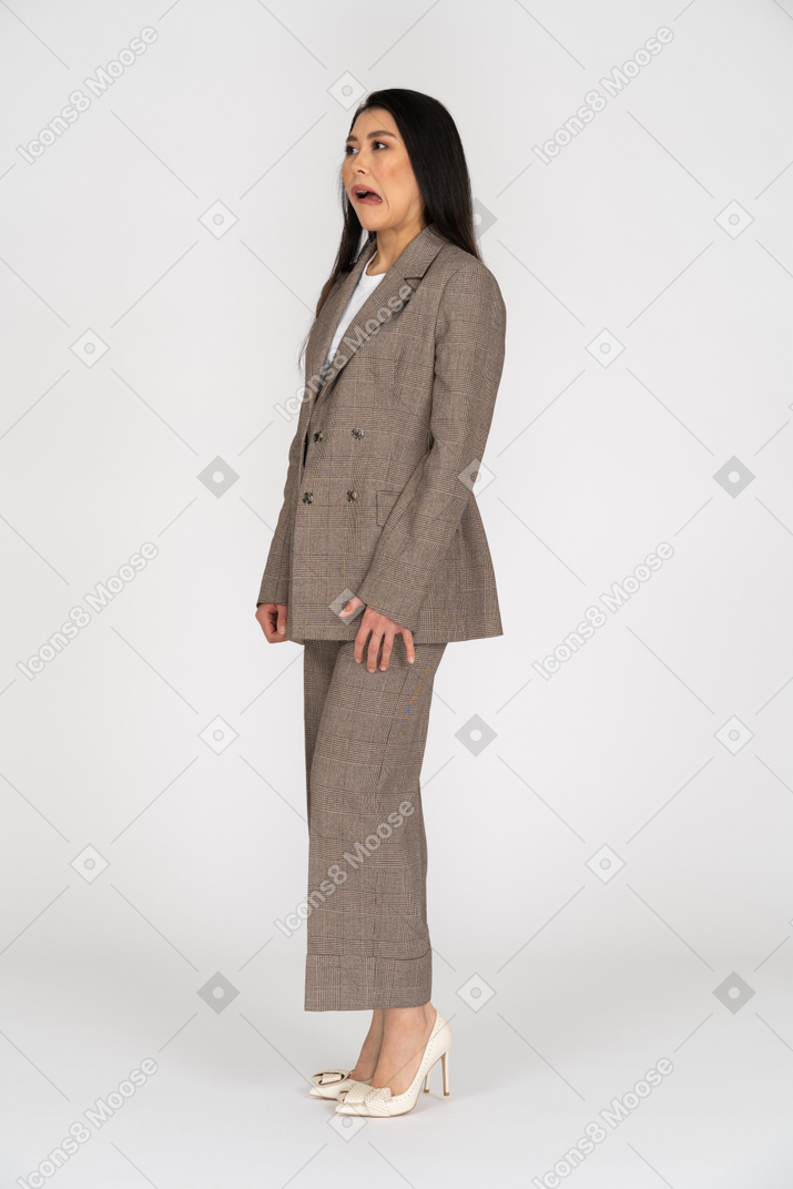 Vista de tres cuartos de una señorita haciendo muecas en traje marrón mirando a un lado