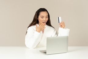 Задыхаясь молодая азиатская женщина делая покупки онлайн