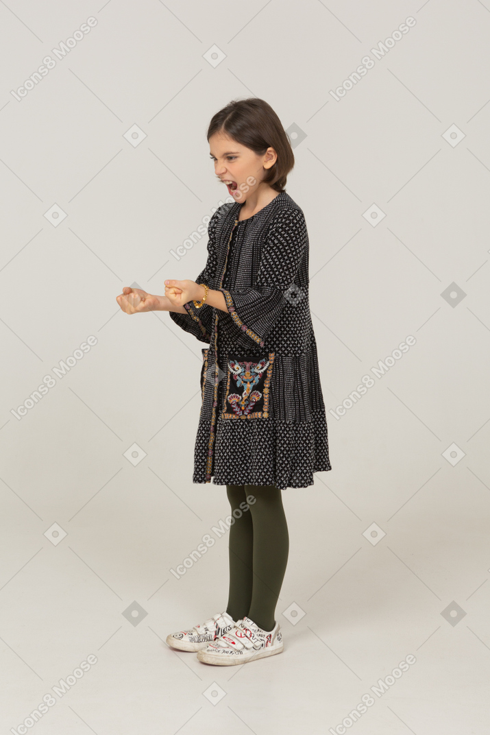 Three-quarter view of a furious little girl in dress clenching fists