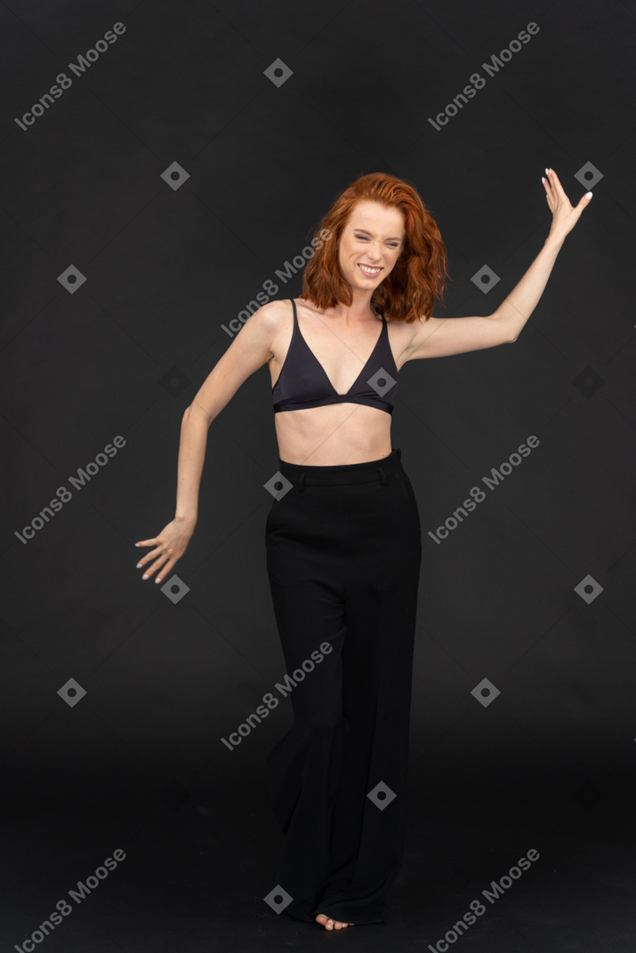 A frontal view of the cute red haired girl posing on the black background