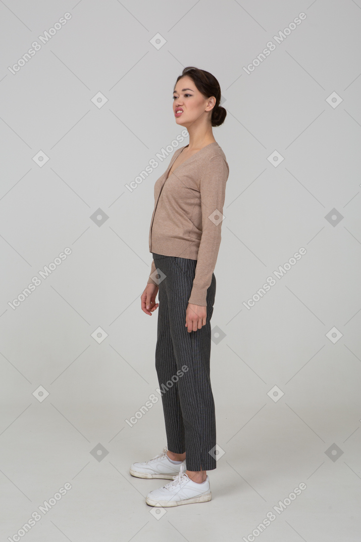 Vista de três quartos de uma senhora fazendo careta em um pulôver e calças olhando para o lado