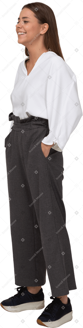 Vista di tre quarti di una giovane donna sorridente in abiti da ufficio che mette le mani in tasca