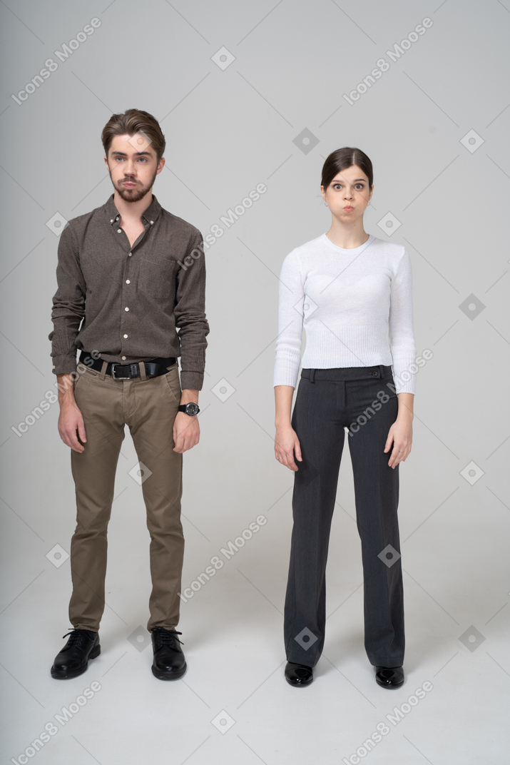 Vista frontal de um jovem casal com roupas de escritório soprando nas bochechas