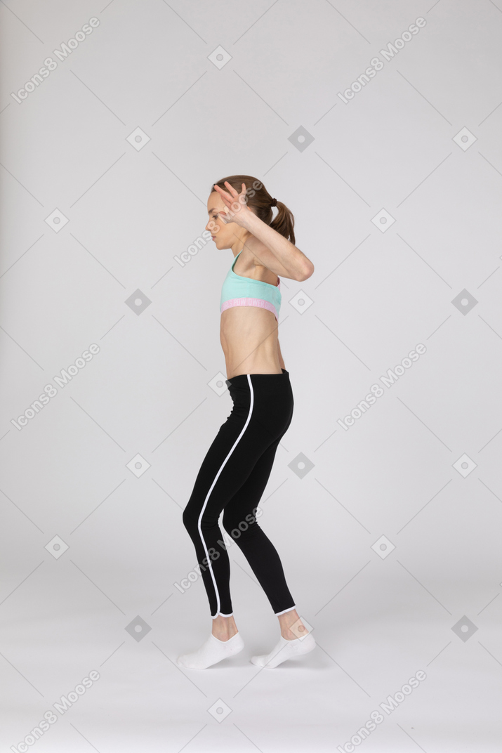 Vista laterale di una ragazza adolescente in abiti sportivi che cammina con cautela in punta di piedi