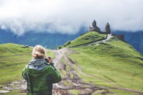 Young woman takes photos with a camera and enjoys the picteresque view