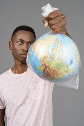 A young man holding a white plastic with the earth globe