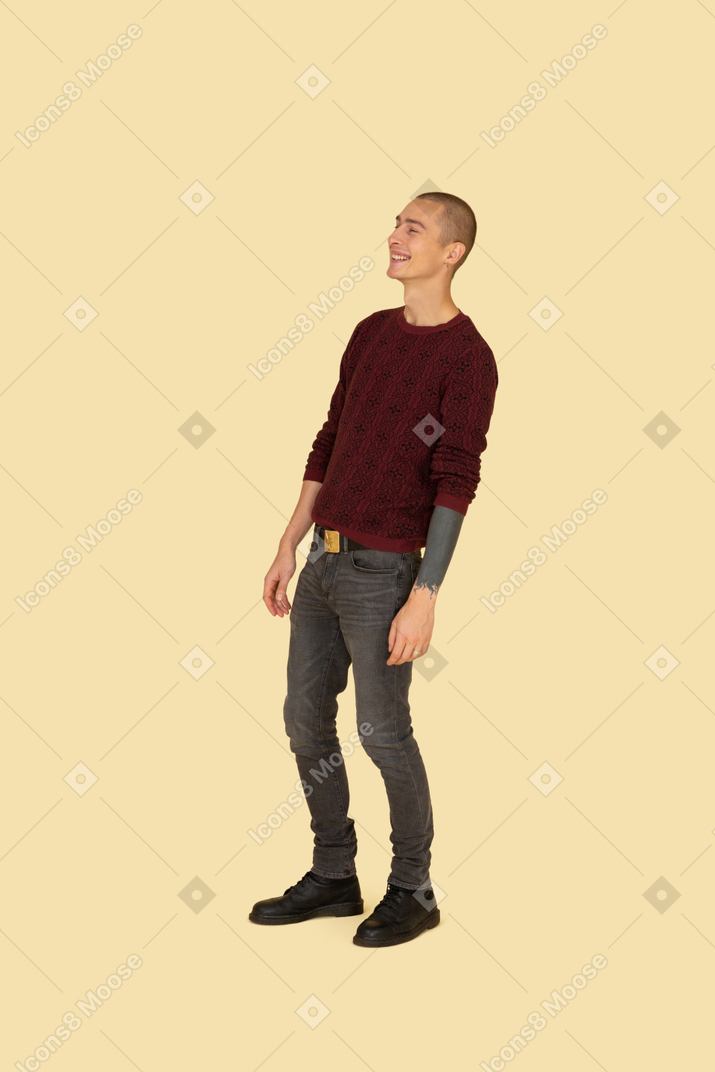 Вид в три четверти смеющегося молодого человека в повседневной одежде, откинувшегося назад