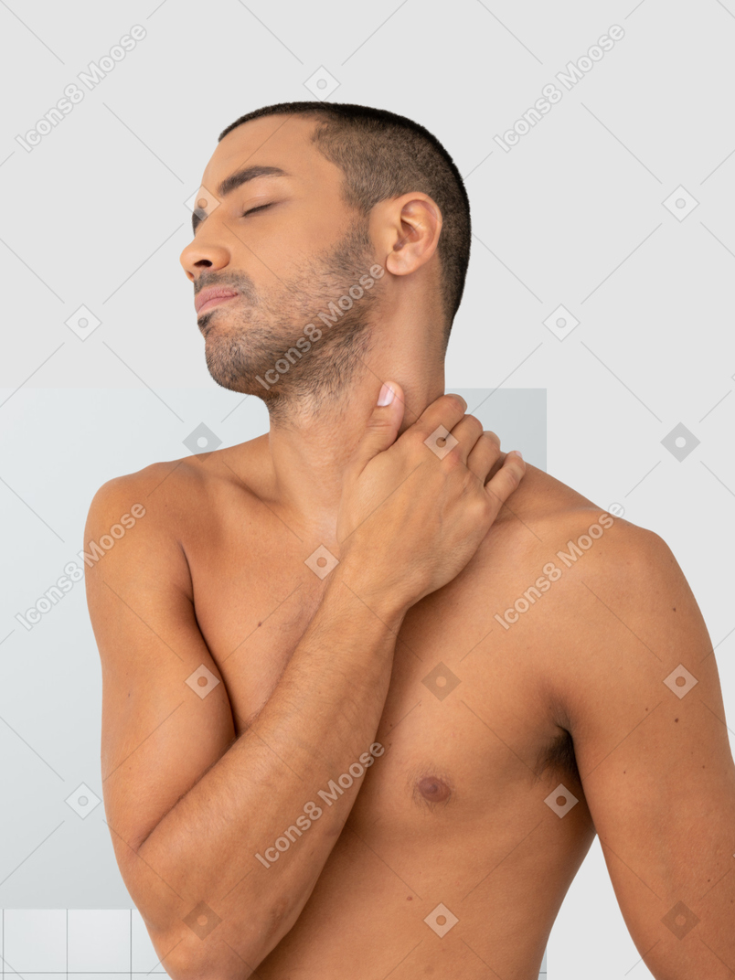 A shirtless man holding his neck in pain