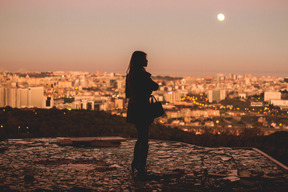 Mujer disfruta de la vista de la ciudad de noche