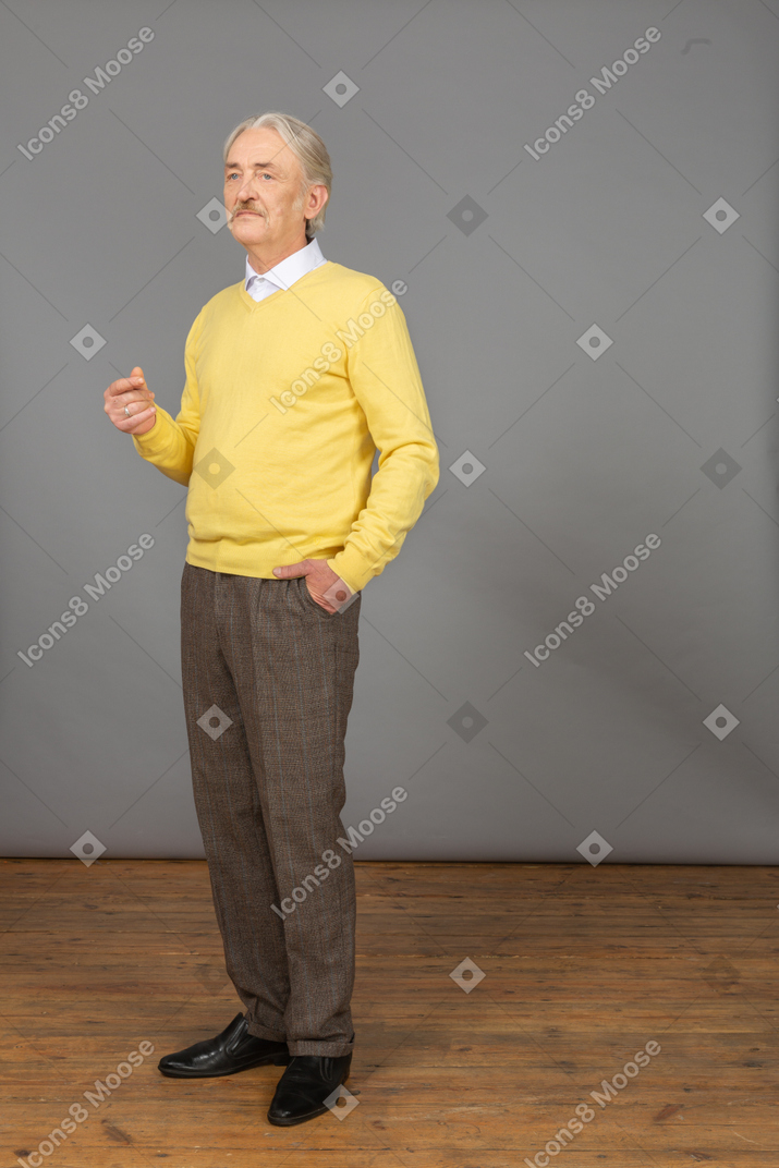 Three-quarter view of a thoughtful old man raising hand and looking aside