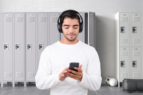 A man wearing headphones looking at a cell phone