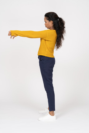 Side view of a girl in casual clothes showing thumbs down