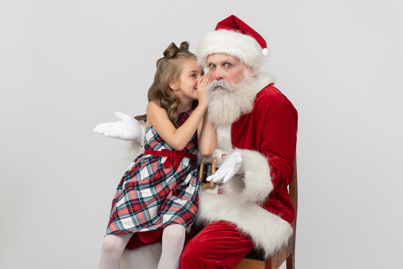Kid girl whispering something on santa's ears